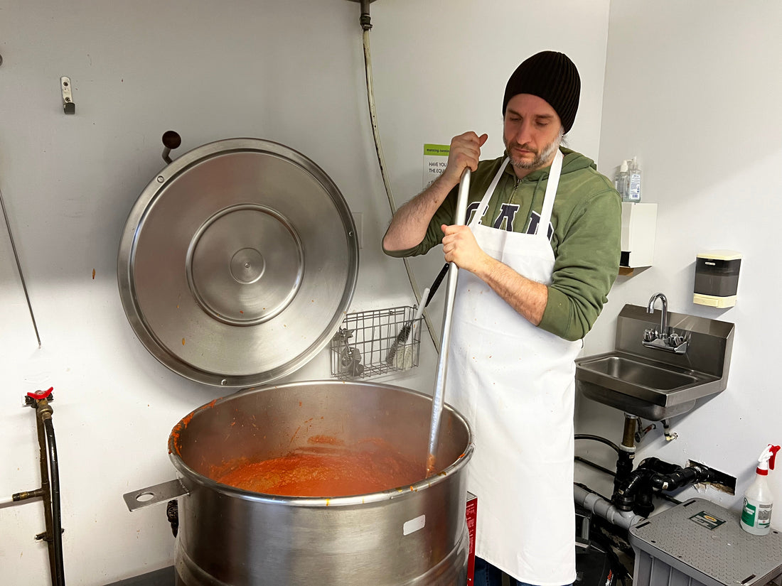 Balkan man stirring a large industrial pot of Spicy Balkan Ajvar